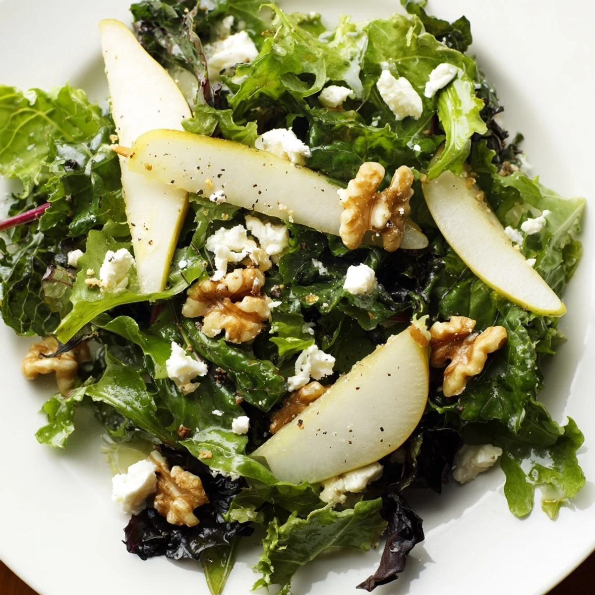 Tossed with a tangy apple cider vinaigrette, this Winter Green Salad with Pear and Walnuts features crumbled goat cheese and pomegranate seeds.
