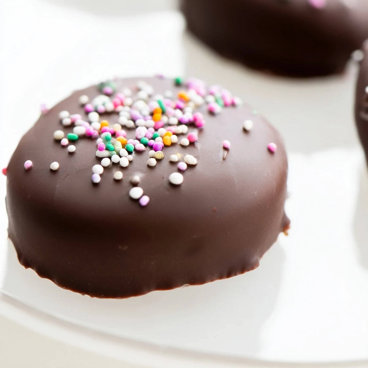 Twelve bright marshmallow Peeps lined up, fully coated in glossy melted chocolate and sprinkled with colorful sugar for a festive Easter treat.  