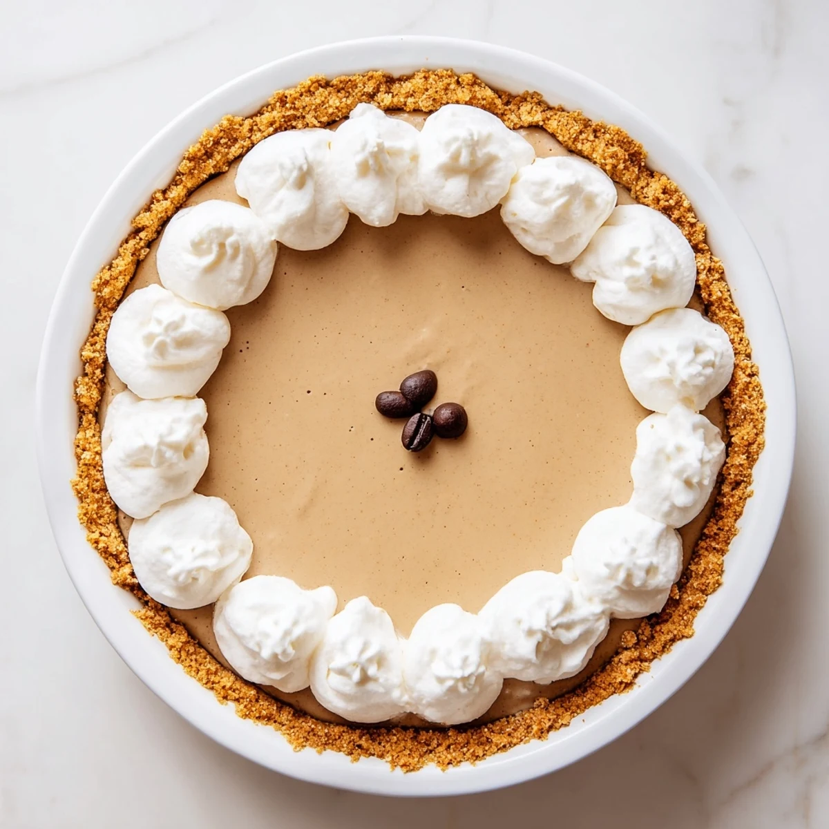 A close-up view of Keto Cold Brew Coffee Pie showing a smooth coffee-flavored layer and a dollop of fresh whipped cream.