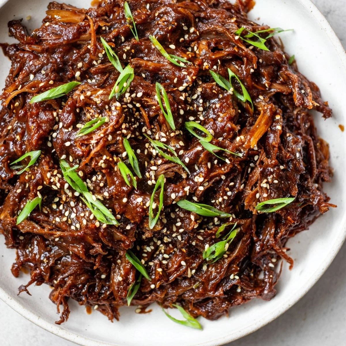 Close up of Slow Cooker Korean Beef in a slow cooker pot, showing juicy beef chunks coated in a rich, reddish sauce.