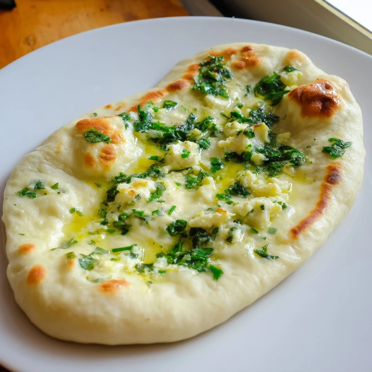 Freshly cooked Cottage Cheese Garlic Naan brushed with melted butter and garlic, showing golden blisters and steam rising.