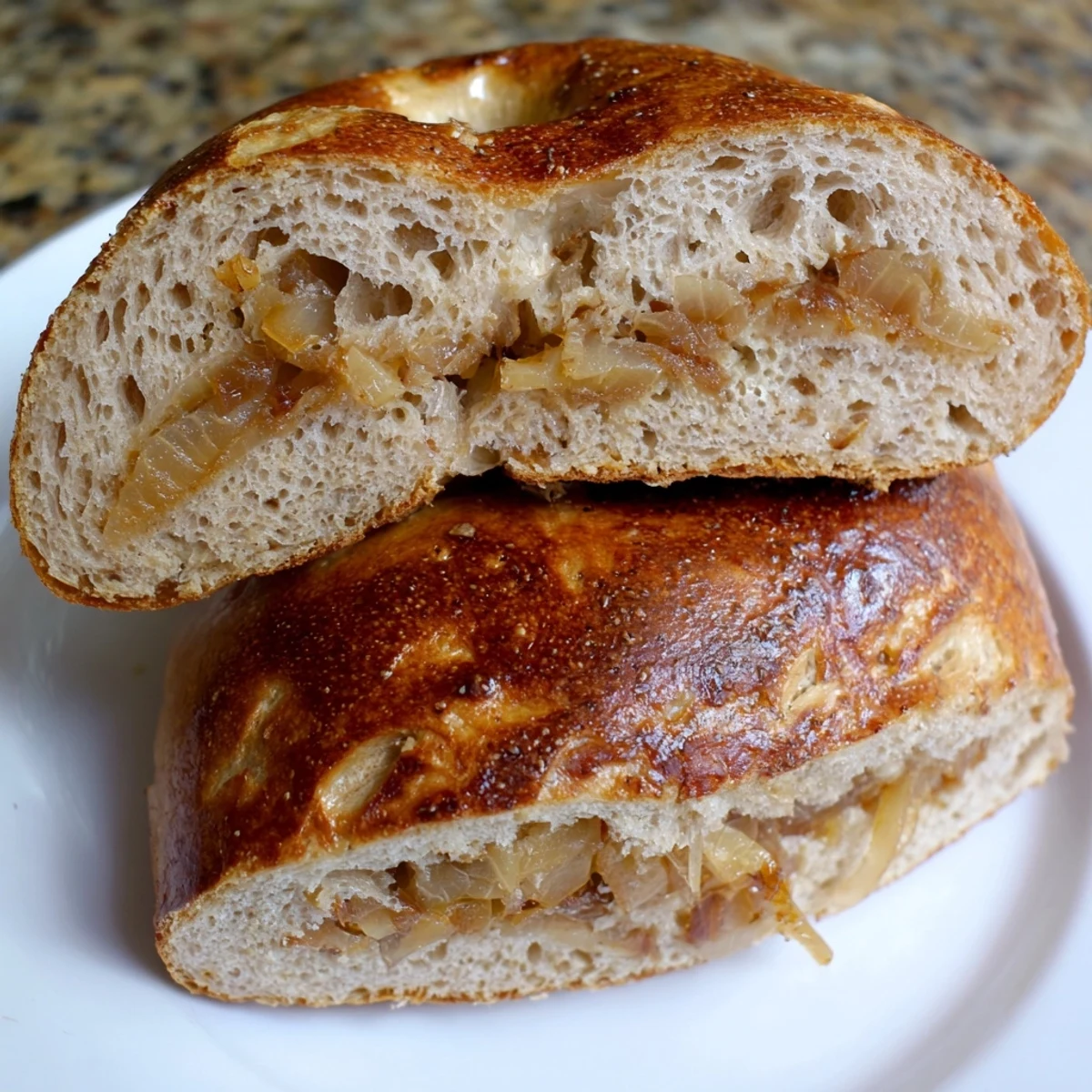 Golden-brown Sourdough Onion Bagels topped with sweet caramelized onions on a wooden board, ready to slice for brunch.