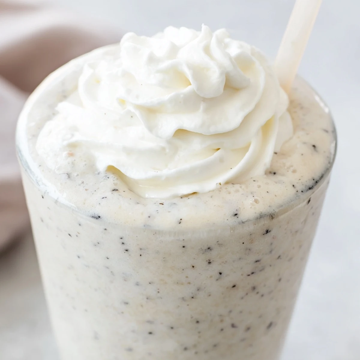 Creamy Vanilla Bean Frappuccino blended with ice and milk served in a clear glass with a straw.