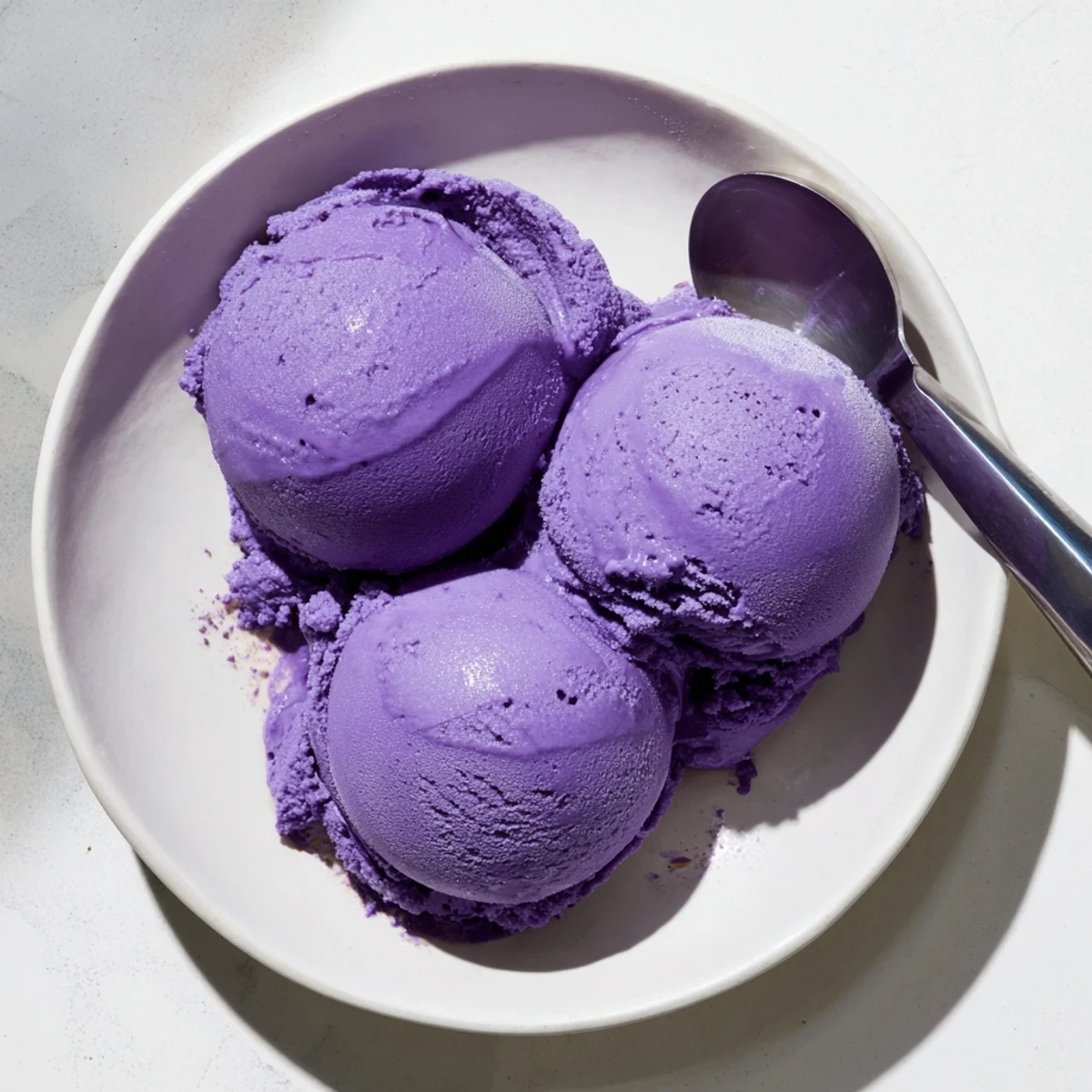 Rich Ube Ice Cream swirled into a cone, creamy texture visible against a rustic wooden table backdrop.