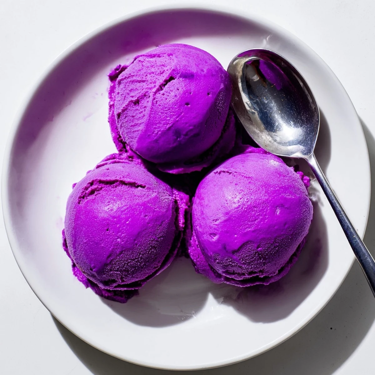 Smooth homemade Ube Ice Cream served in a waffle bowl, garnished with sweet macapuno strings for extra texture.
