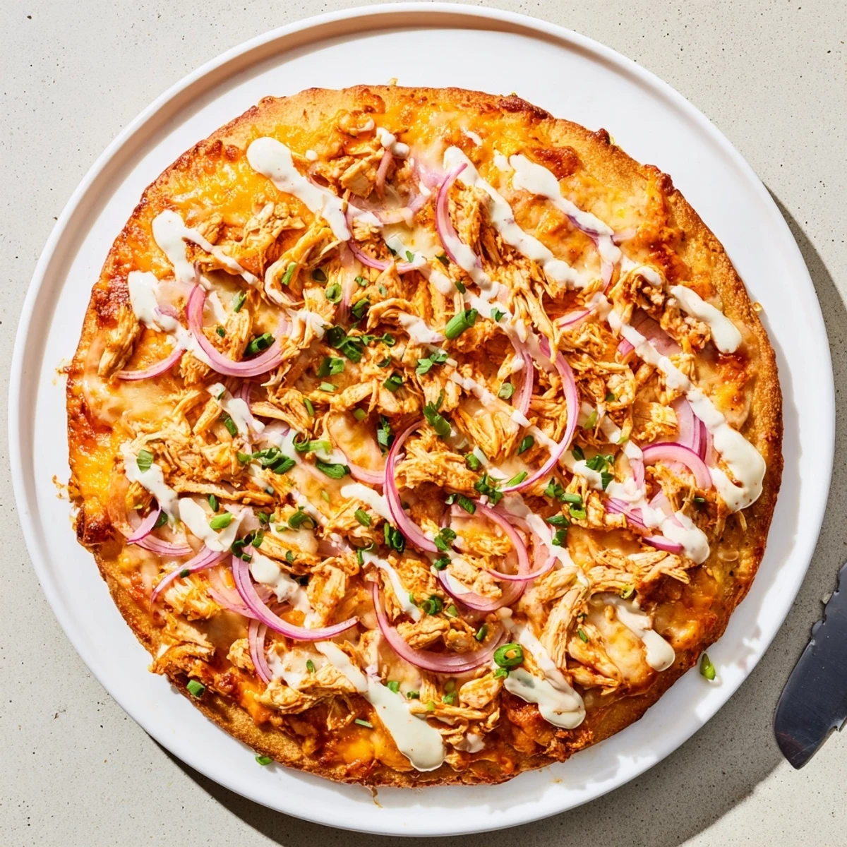 A slice of Bold Buffalo Chicken Pizza with melted mozzarella and cheddar cheese, topped with scallions and red onion.