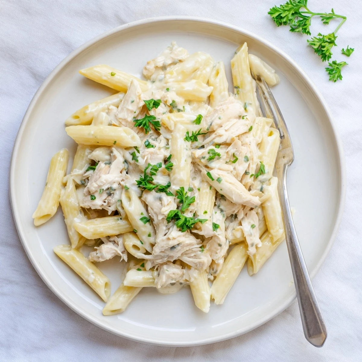 A slow-cooker view of tender Crockpot Garlic Parmesan Chicken Pasta tossed in a creamy, garlicky sauce with penne noodles.