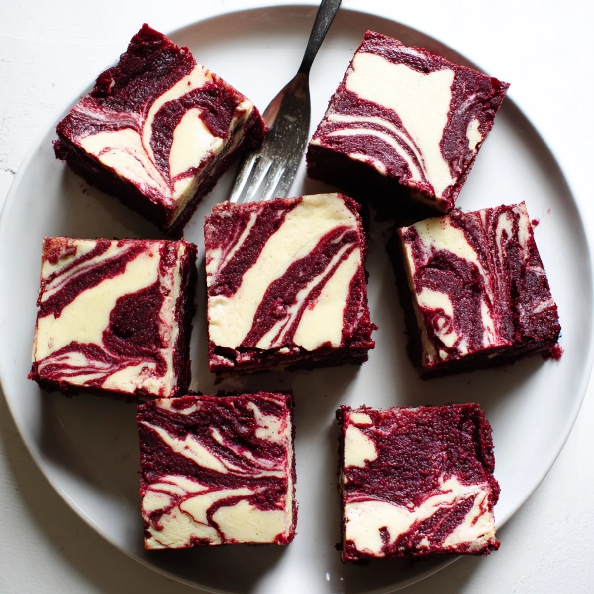 Freshly baked Red Velvet Cheesecake Brownies cut into squares, revealing fudgy texture and marbled cheesecake layers, ready to serve.
