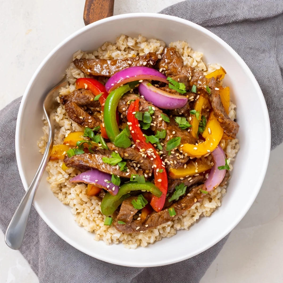 Vibrant stir-fried beef and crisp multicolored peppers garnished with sesame seeds in this Healthy Beef and Pepper Rice Bowl