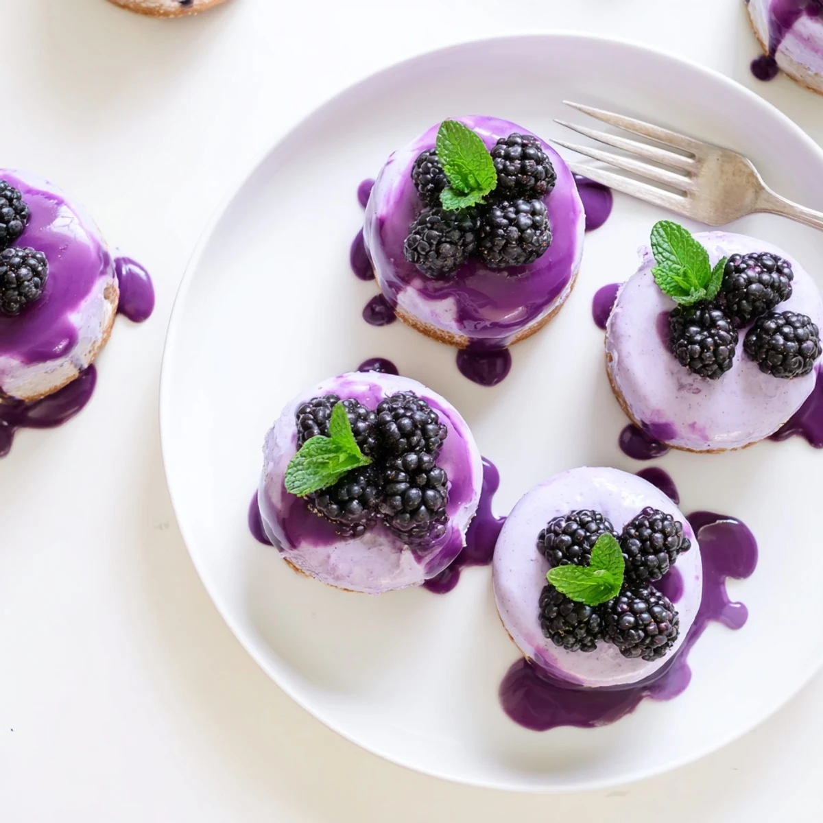 Individual desserts featuring light airy blackberry mousse on delicate vanilla sponge base