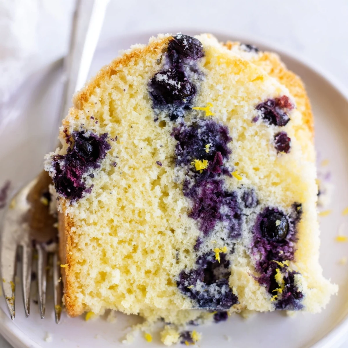 Tall airy blueberry chiffon cake with speckled purple fruit inside inverted on cooling rack