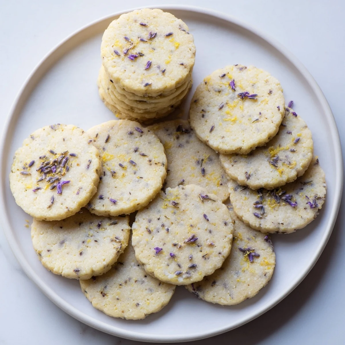 Golden lemon lavender cookies cooling on a wire rack with visible purple lavender buds