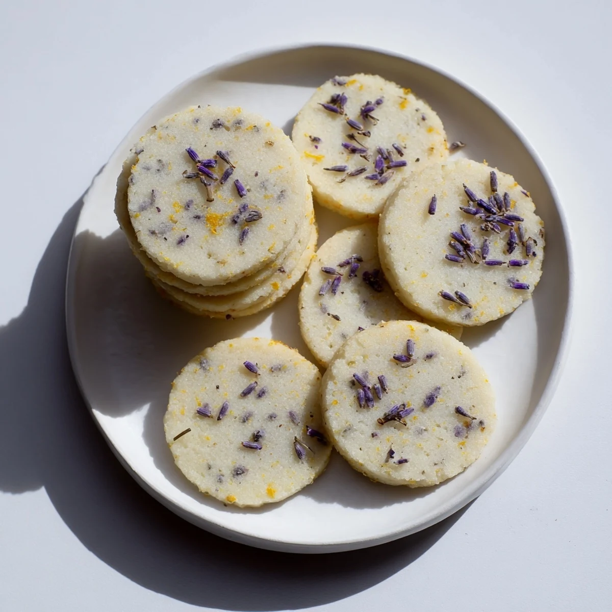 Freshly baked lemon lavender cookies with zesty garnish resting on parchment paper-lined baking sheet