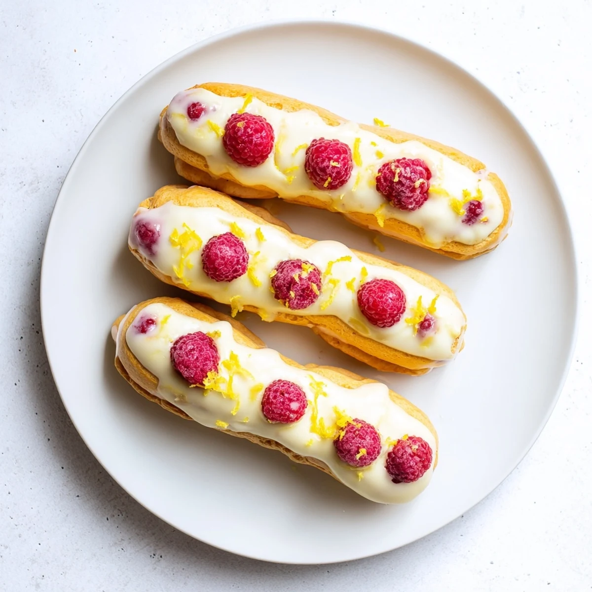 Elegant choux pastry puffs sandwiching bright lemon mousse and juicy ripe raspberry garnish