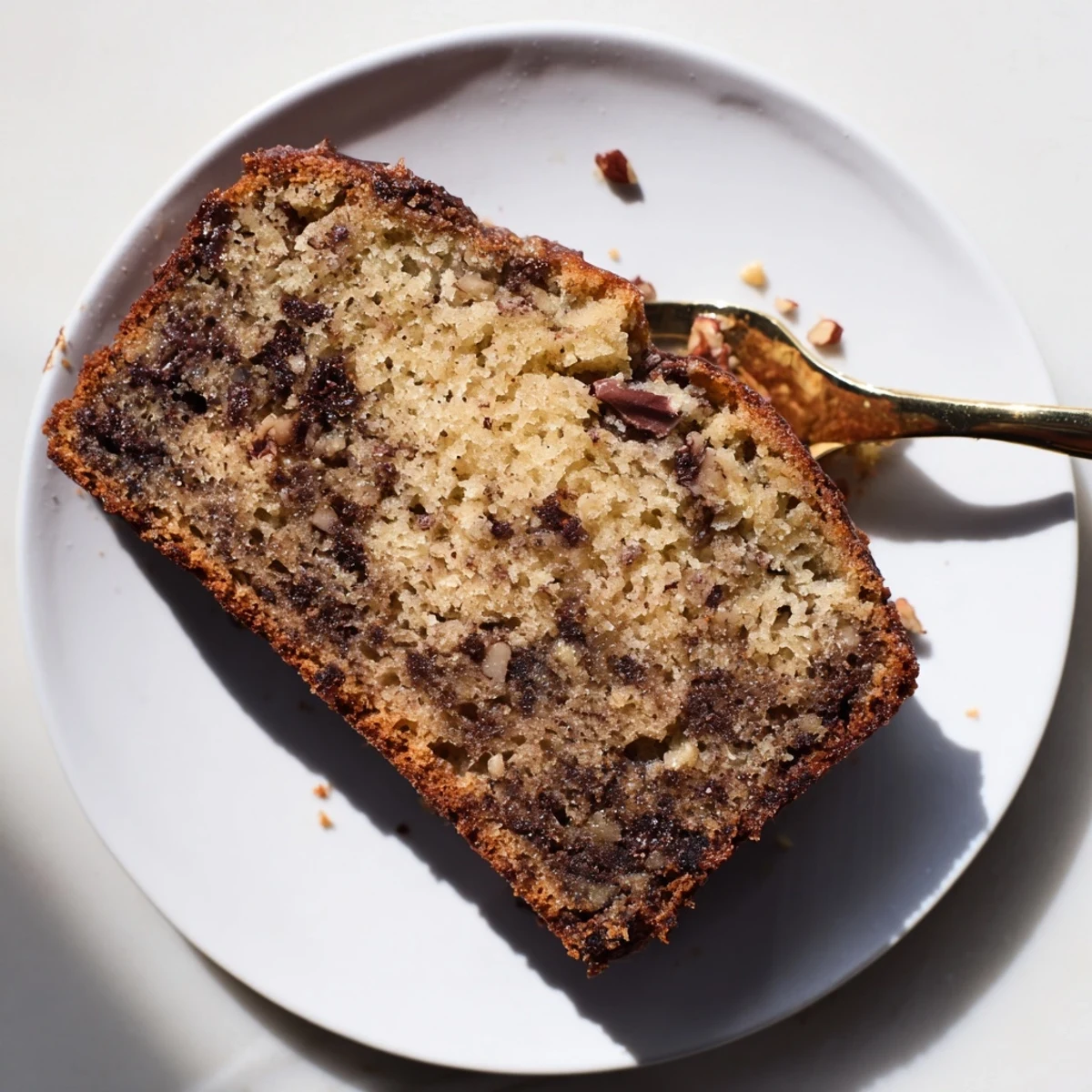 Freshly baked Best Ever Banana Bread cooling on wire rack, golden crust glistening under natural light with sliced bananas nearby