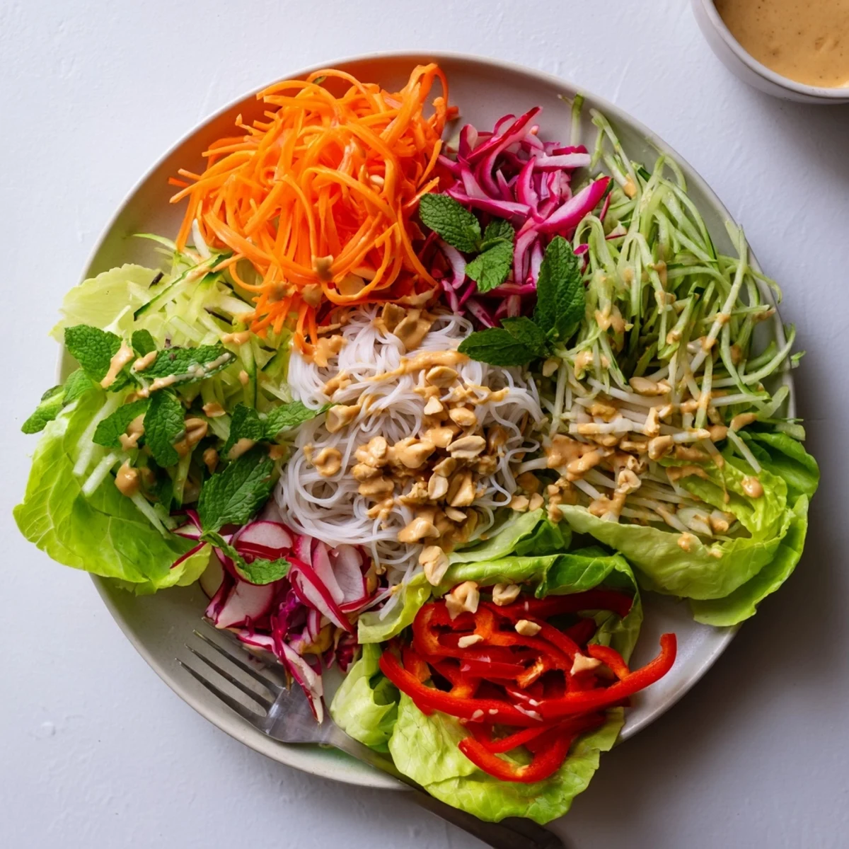 Colorful spring roll salad with peanut dressing featuring crisp vegetables and fresh herbs drizzled with creamy sauce