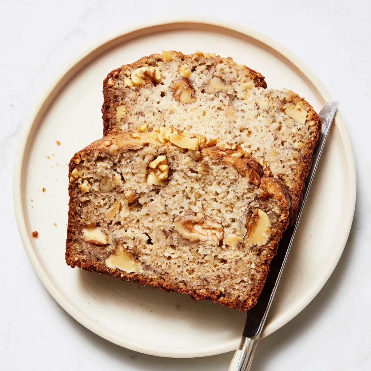 Golden brown ultimate banana nut bread loaf studded with toasted walnuts on a wooden cutting board