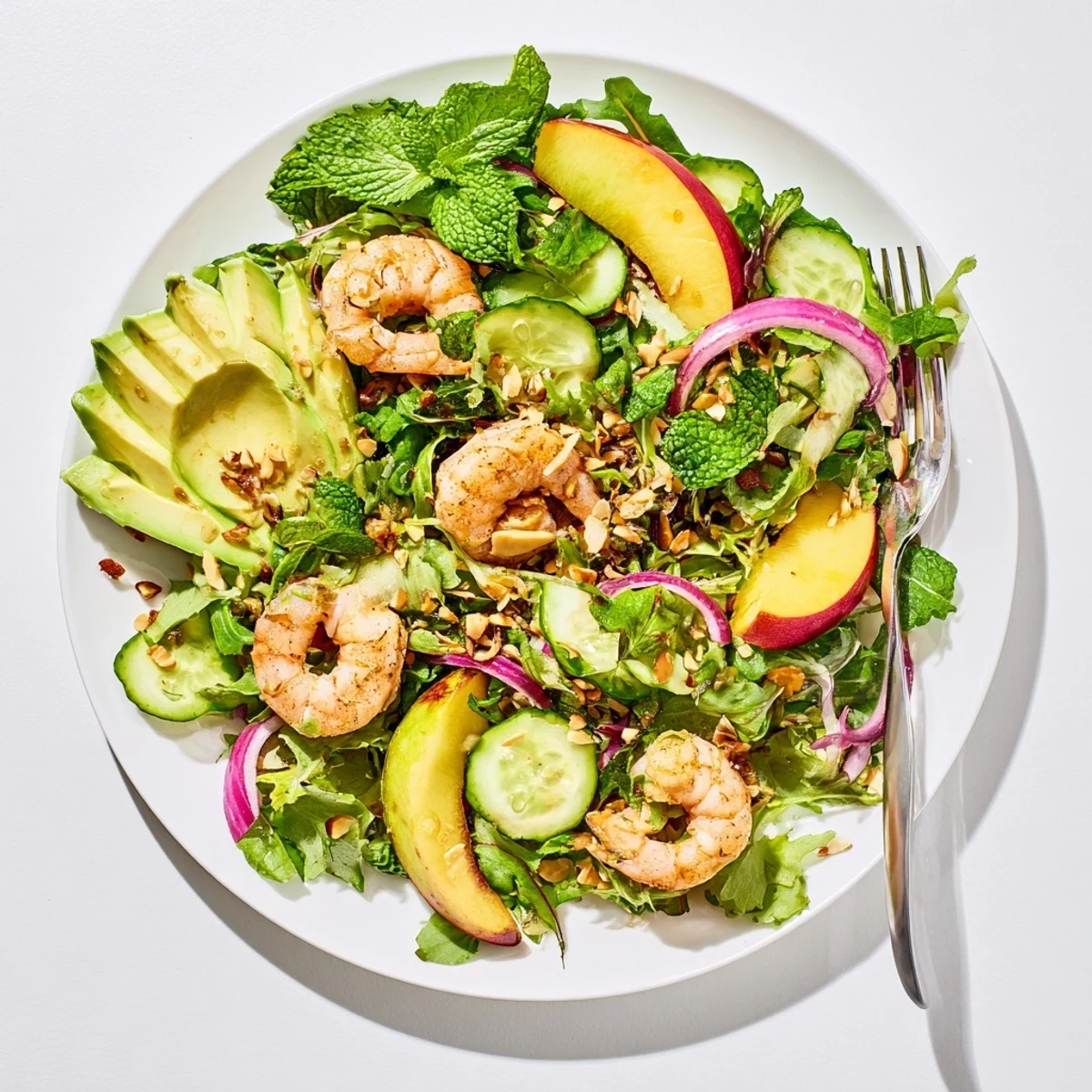 Vibrant summer salad featuring succulent grilled shrimp, ripe nectarines, avocado, cucumber, and honey lime vinaigrette