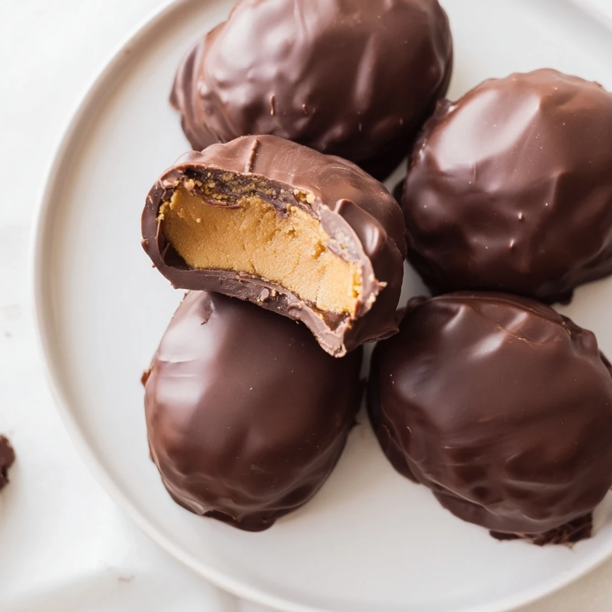 Handmade peanut butter Easter eggs coated in glossy dark chocolate on a white plate
