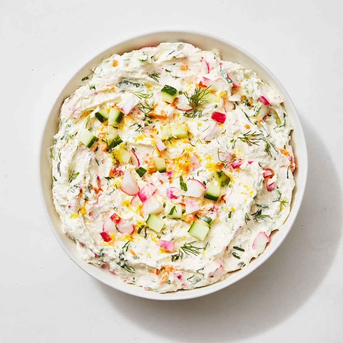 Creamy Easter dip served in white bowl surrounded by colorful fresh vegetables and herbs