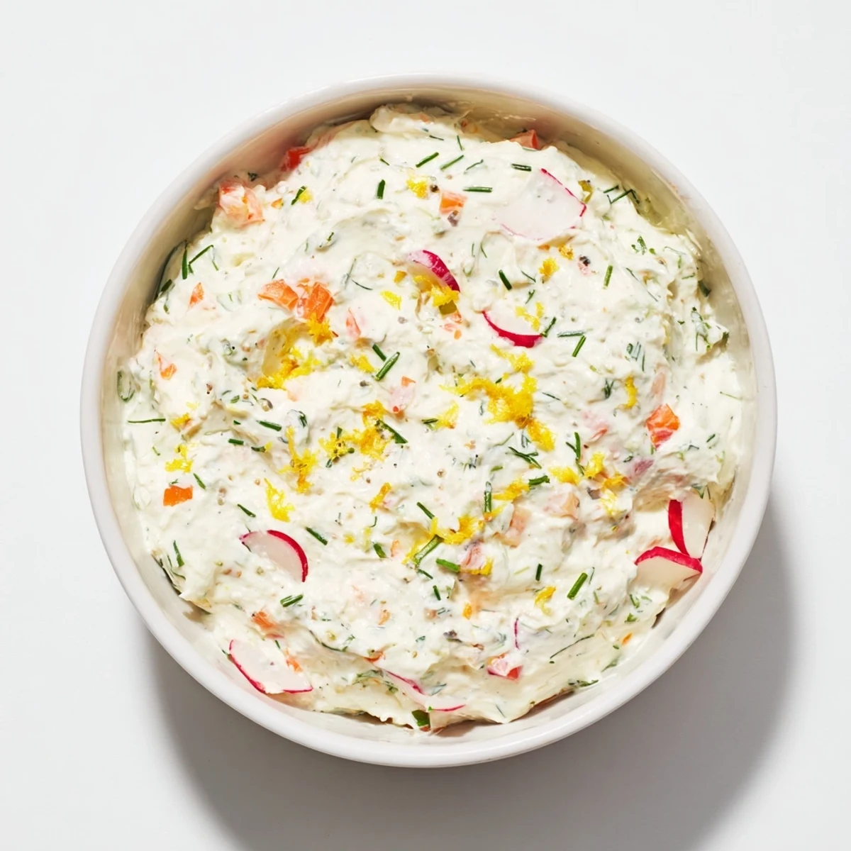 Smooth white creamy Easter dip with fresh herbs served alongside crisp carrot sticks and crackers