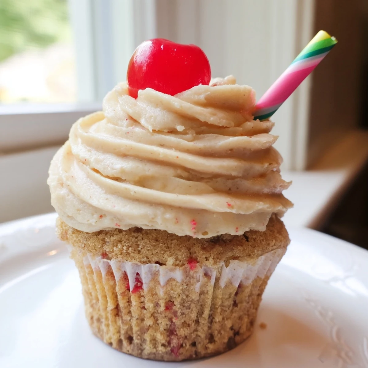 Banana milkshake cupcakes with fluffy vanilla frosting garnished with whipped cream and striped straws