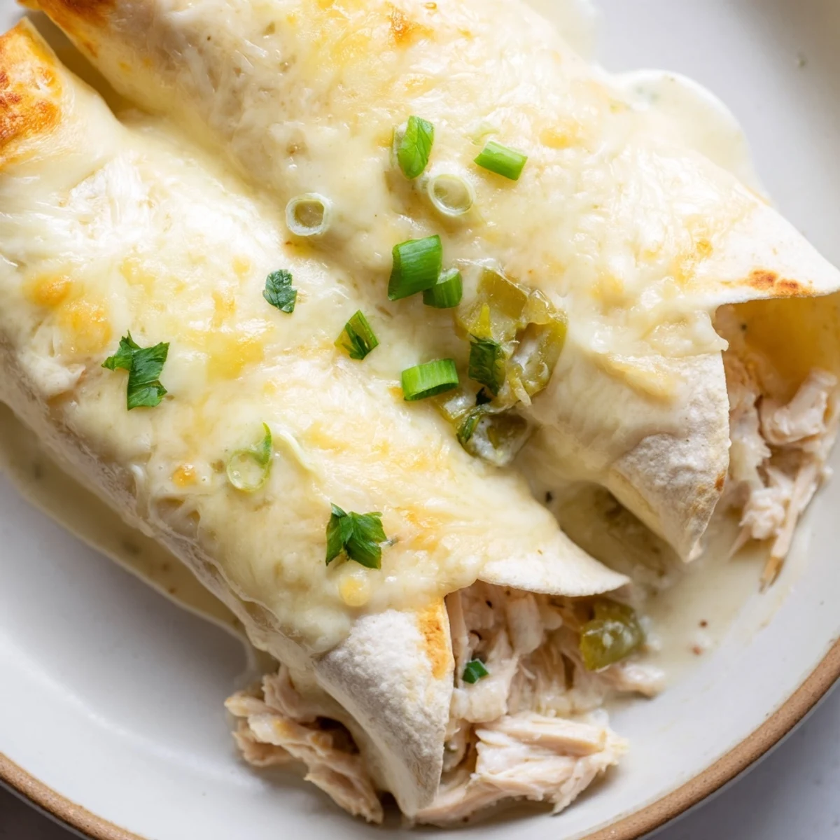 A slice of Creamy White Chicken Enchiladas plated with cilantro and lime wedge