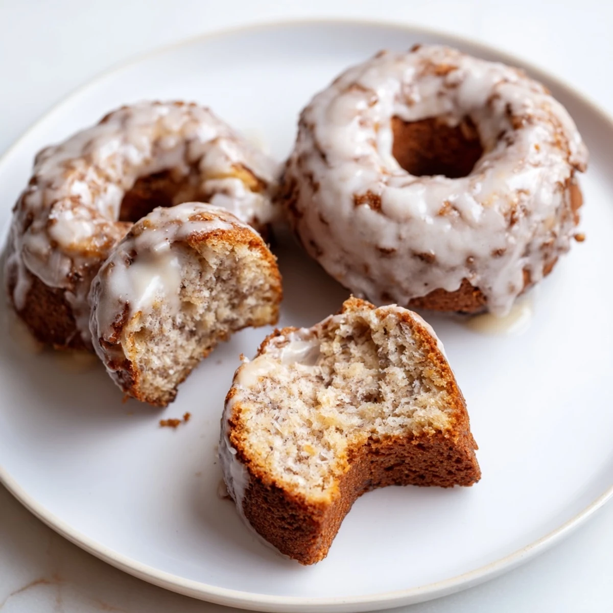 Glazed Banana Donuts arranged on a plate, moist crumb, glossy vanilla glaze