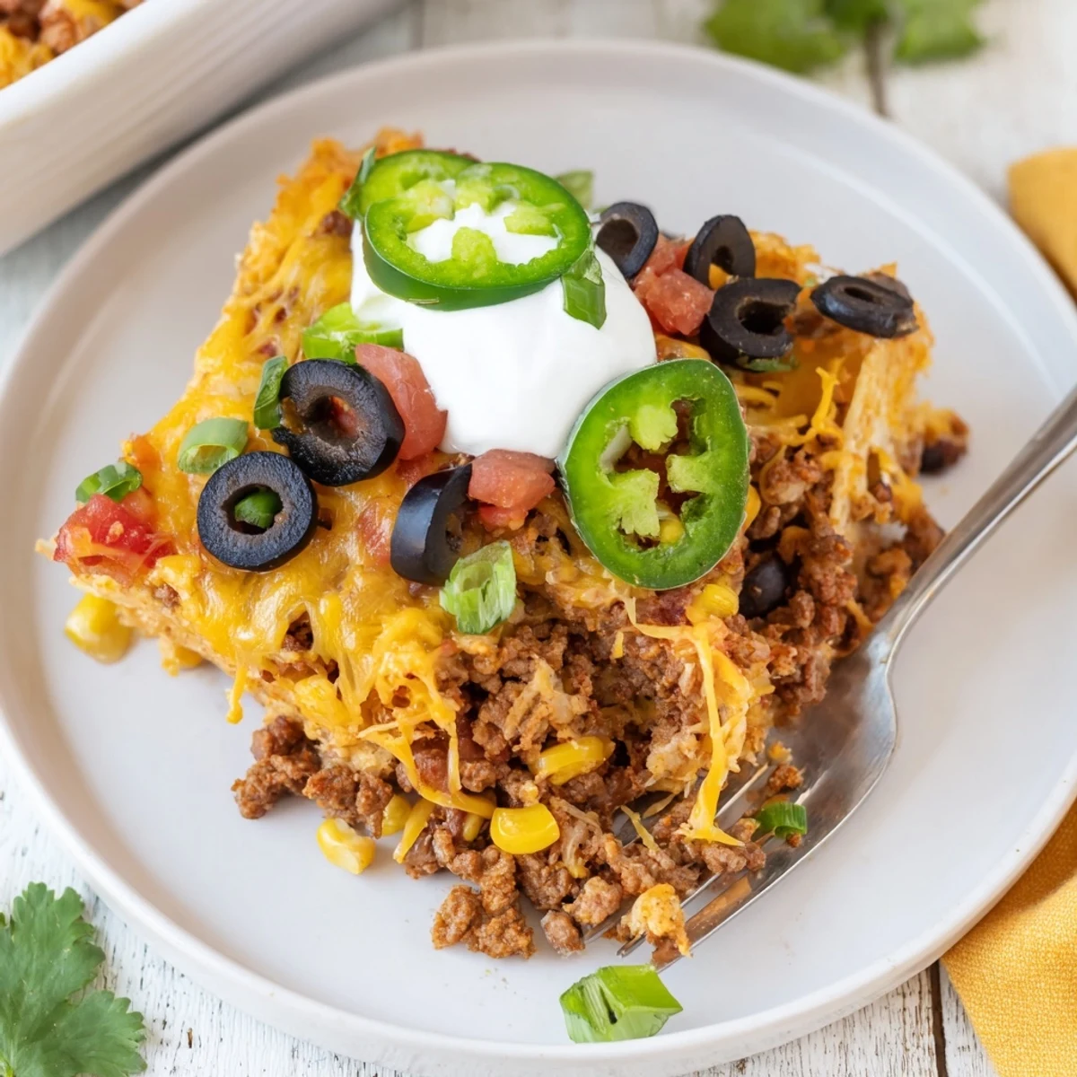 Bubbling Cheesy Nacho Casserole with golden edges, topped with cilantro and jalapeños.