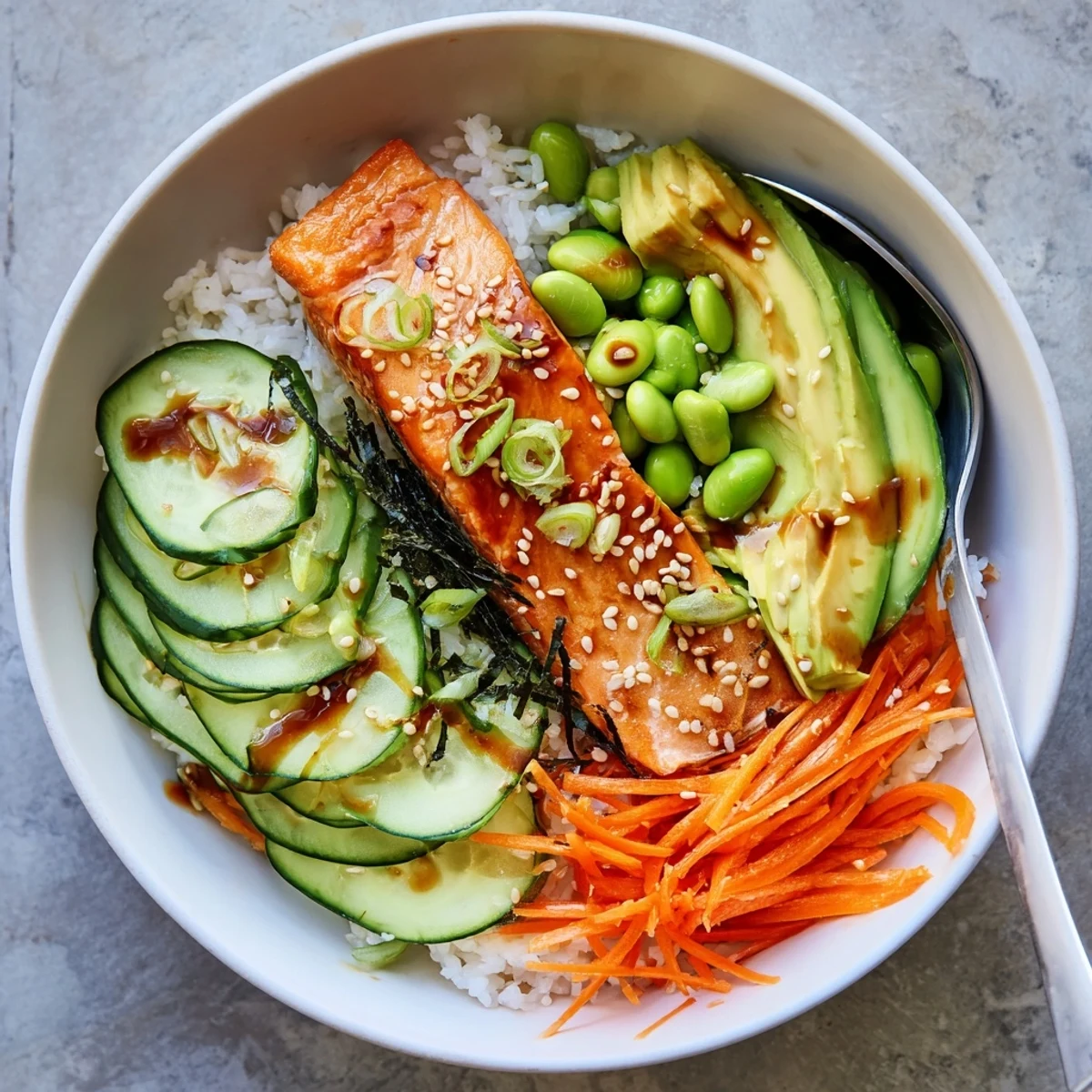 Vibrant crispy salmon and rice bowl topped with fresh avocado cucumber and savory sesame sauce