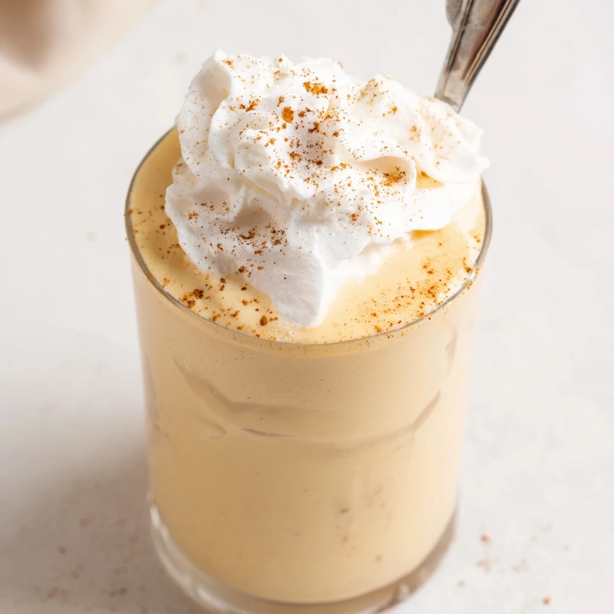 Creamy keto eggnog topped with whipped cream and dusted with nutmeg for holidays