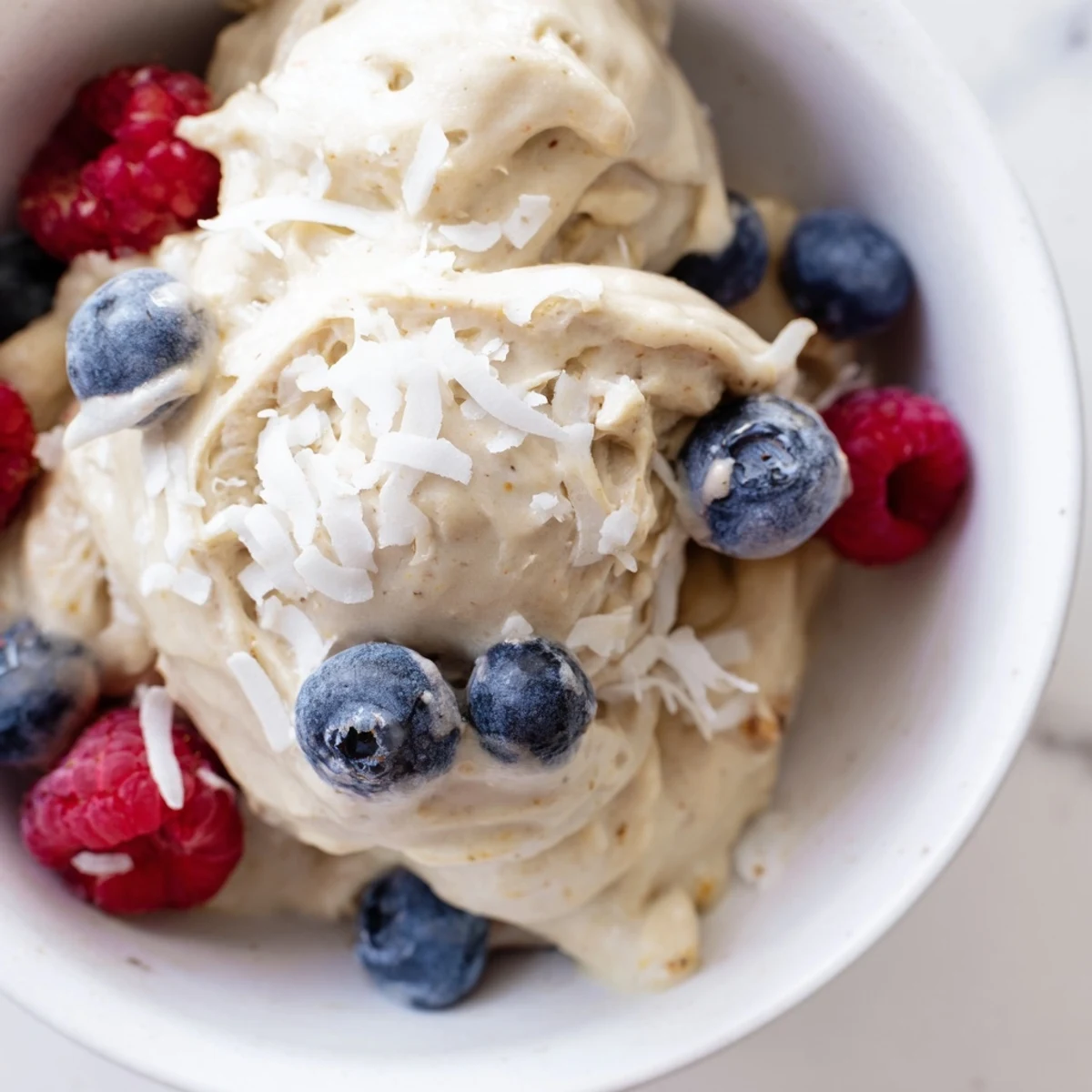 Creamy healthy nice cream bowl topped with fresh berries and coconut flakes for a guilt-free vegan dessert