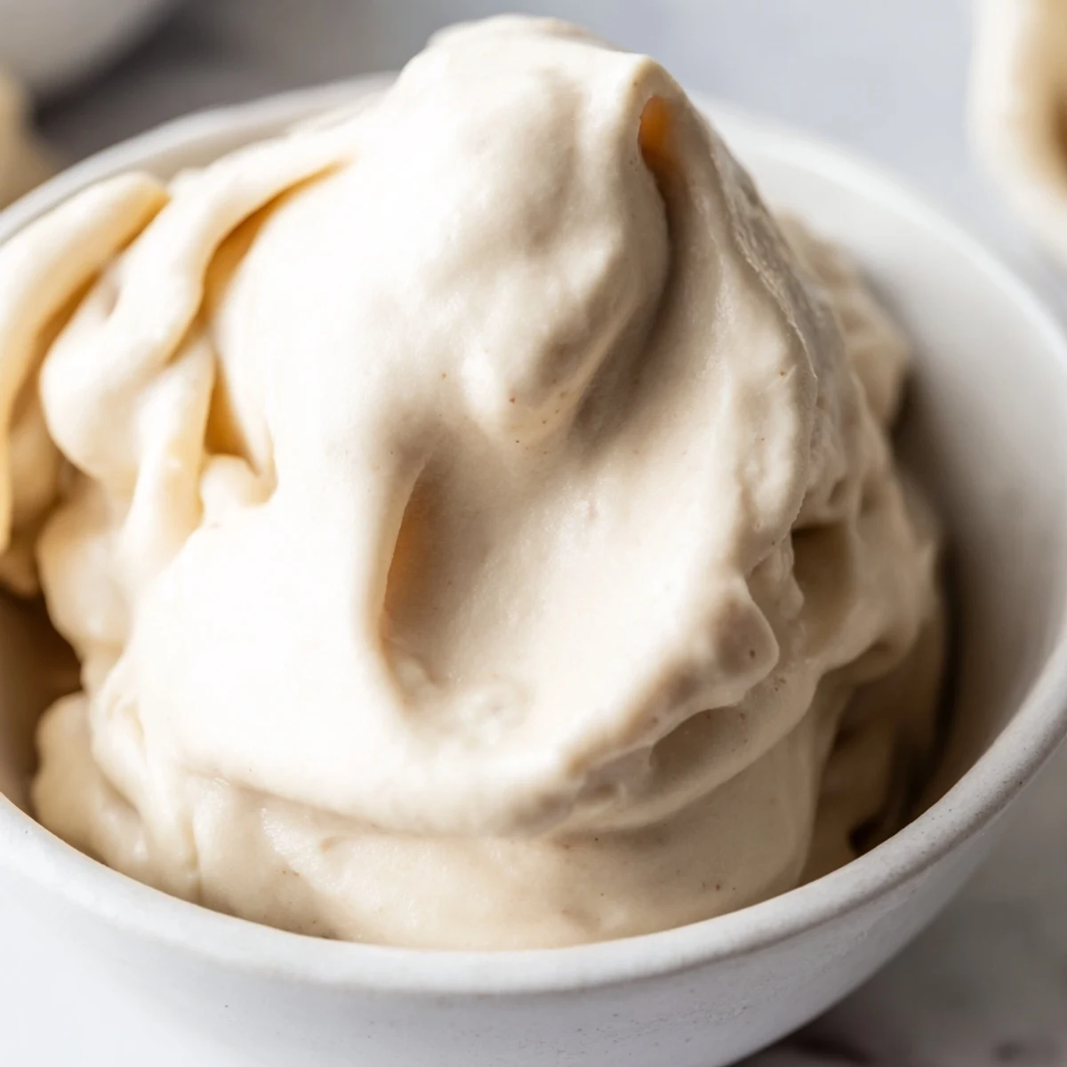 Creamy banana nice cream swirled into bowls topped with fresh fruit slices and dark chocolate chips