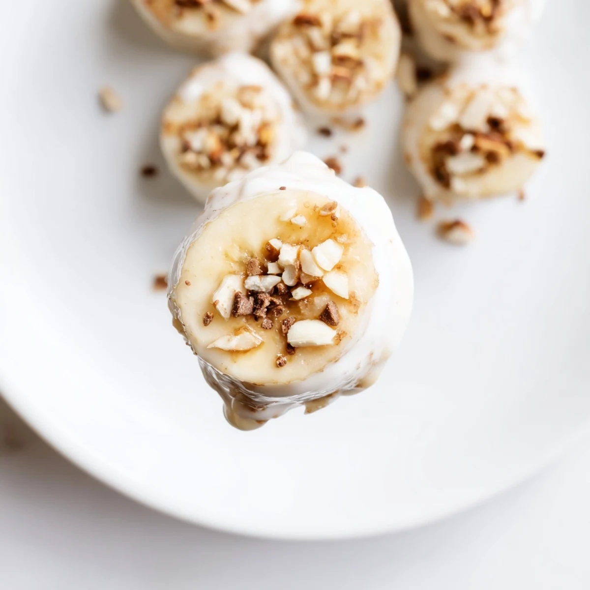 Frozen Banana Yogurt Bites arranged on tray, topped with chopped nuts and coconut