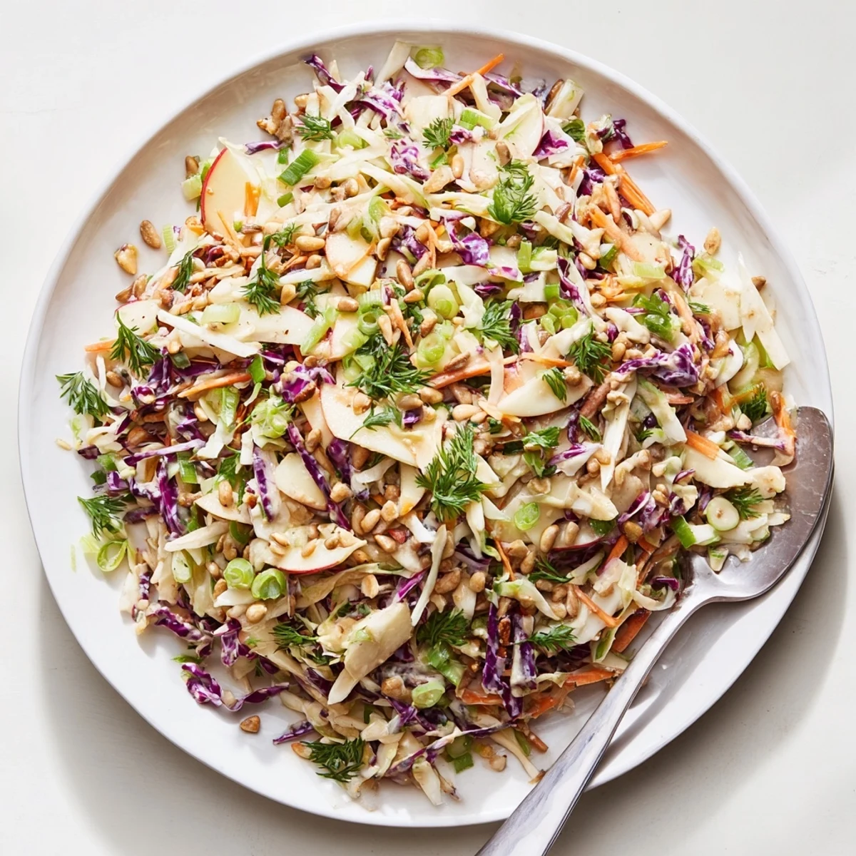 Colorful bowl of apple coleslaw topped with parsley and sunflower seeds for summer picnics