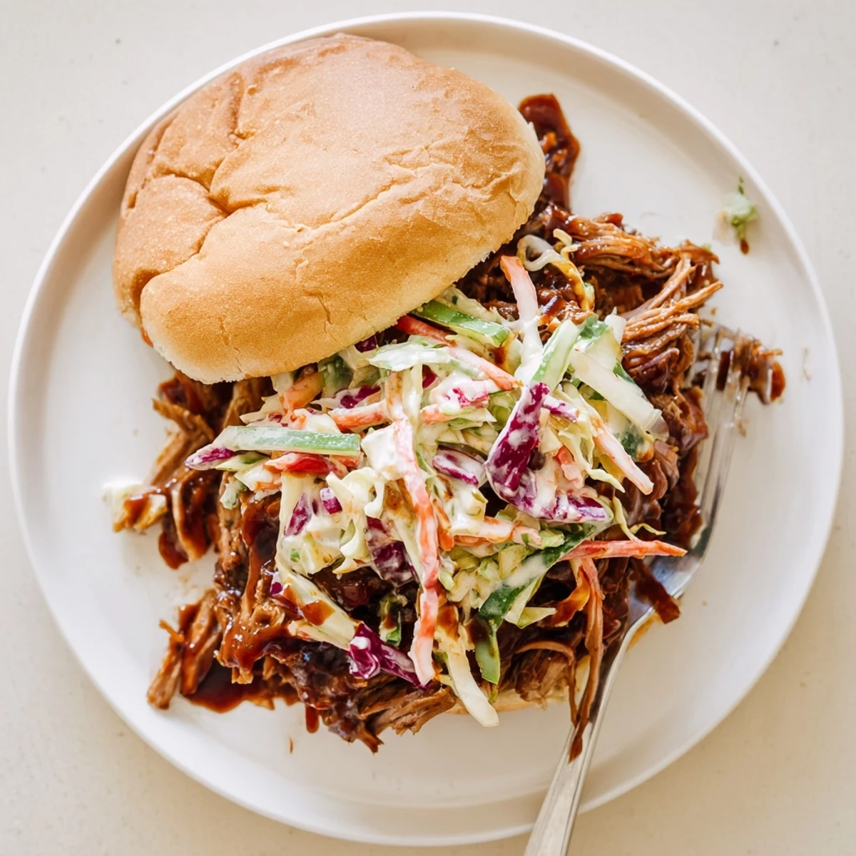 Slow-cooked smoky BBQ beef sandwiches featuring shredded meat and fresh colorful coleslaw topping