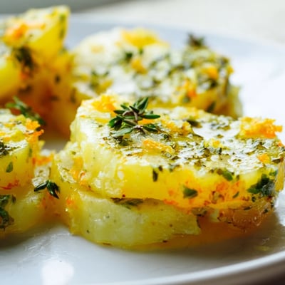 Roast herb chilli and orange butter hasselback potatoes are baked until tender inside and served hot with a vibrant citrus aroma.