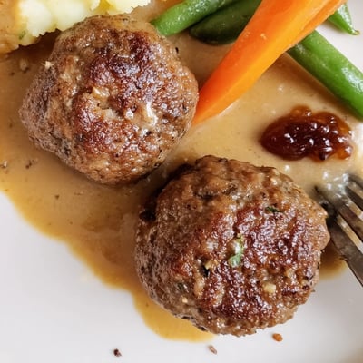 Plate of Homemade Ikea Meatballs glistening with sauce, garnished with lingonberry jam